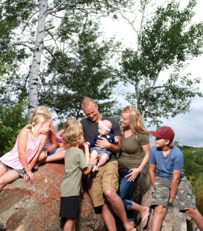 Family poses outside on a boulder