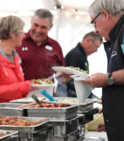 People grabbing food from a buffet table