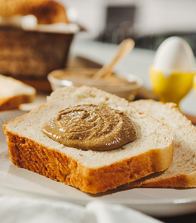 Two thick slices of heart bread on a light coloured place. The slice laying on top has a swirl of nut butter in the centre.